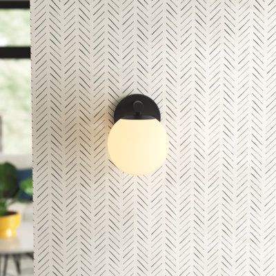 a black and white wall mounted light on the side of a wall with geometric pattern