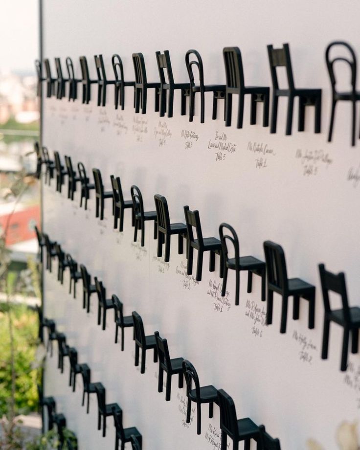 there are many chairs lined up on the white wall and one is black in color