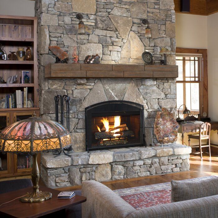 a living room with a fire place and couches in front of a stone fireplace