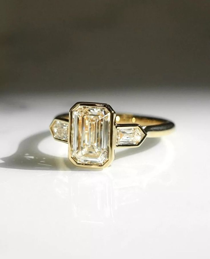 an emerald and diamond ring on a white surface