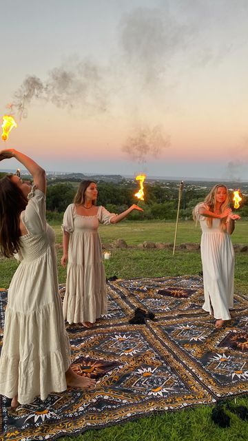 three women holding torches in their hands while standing on top of a rug with grass