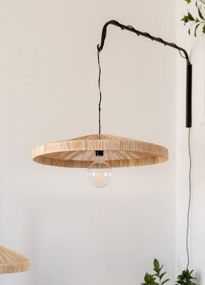 a wooden light fixture hanging from the ceiling in a room with white walls and potted plants