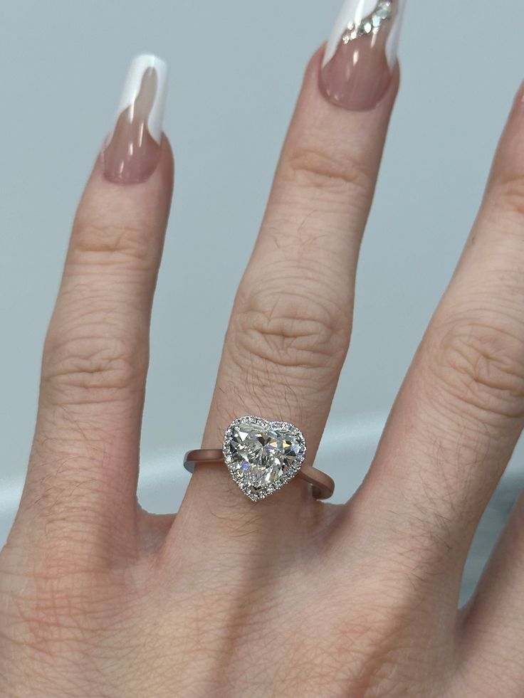 a close up of a person's hand with a diamond ring on their finger