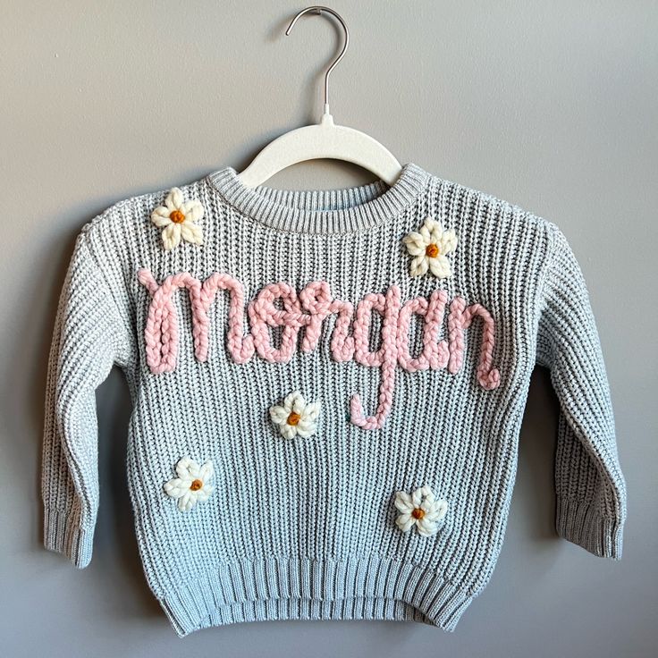 a sweater that says happy on the front and flowers on the back, hanging from a hanger