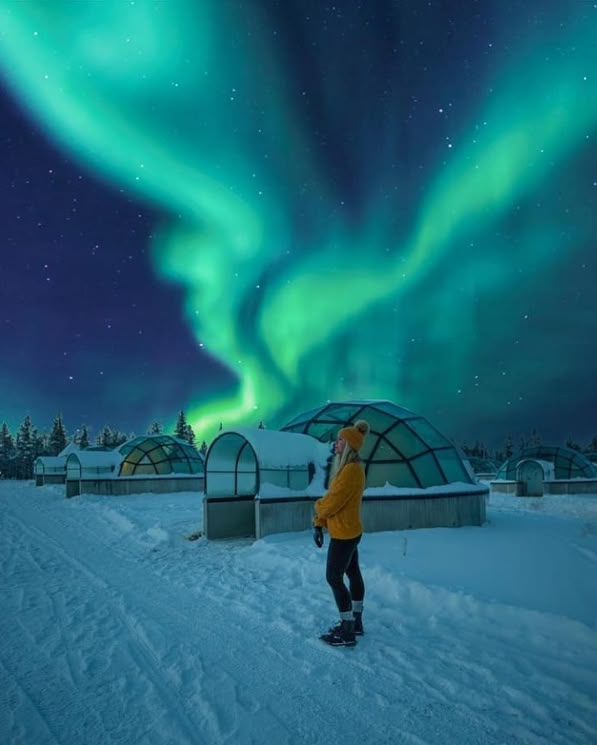 a person standing in the snow under an aurora bore