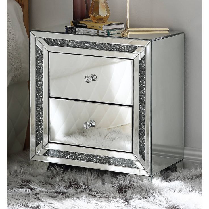 a mirrored night stand with two drawers and a mirror door on the top, in front of a white fur rug