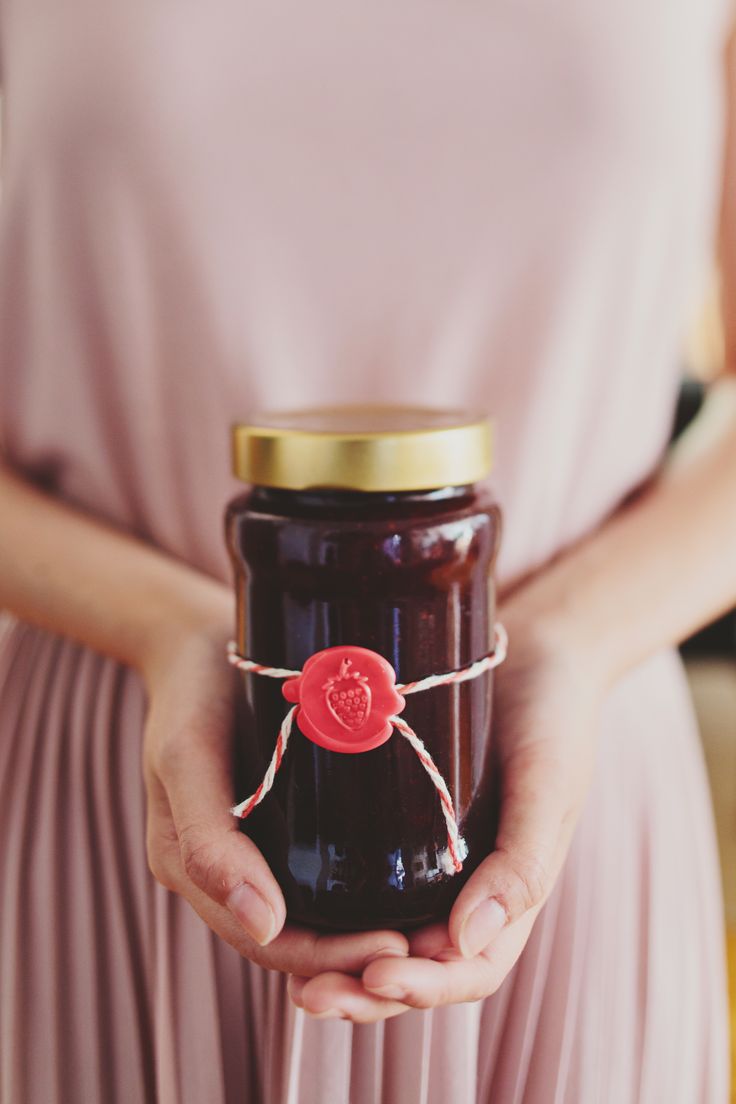 a woman holding a jar of jam in her hands