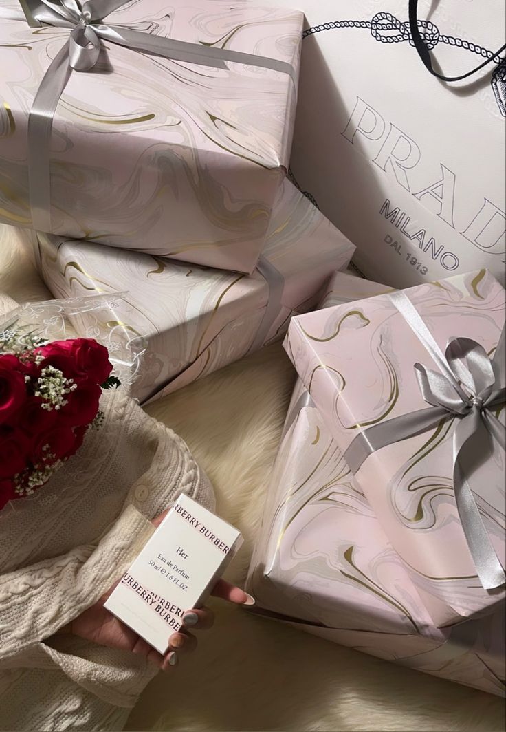 a woman holding a red rose in her hand next to many wrapped presents and gifts