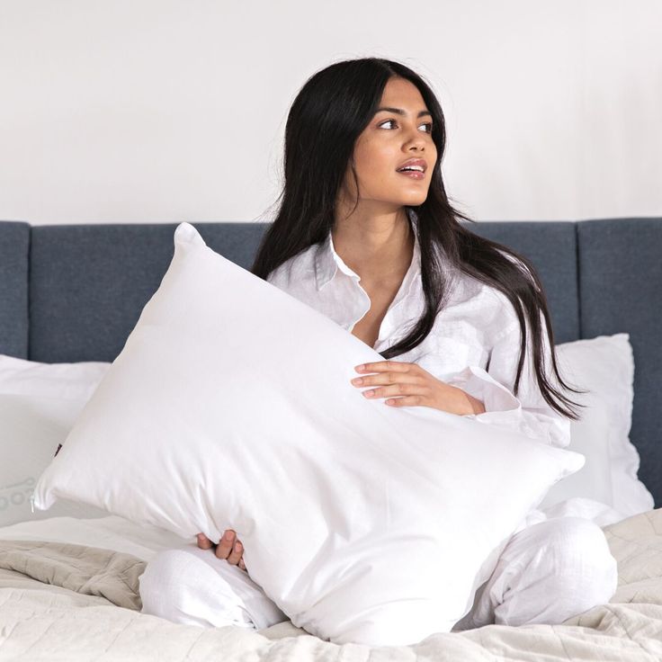 a woman sitting on a bed holding a pillow