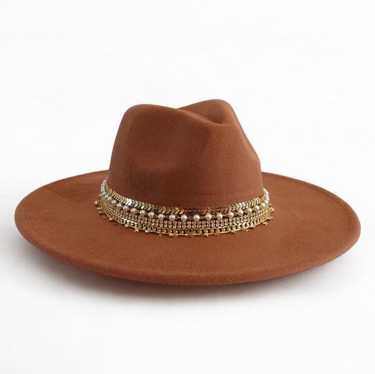 Dazzle in Nashville with this stunning vegan suede rancher hat, handcrafted with 5 rows of sparkling jewelry and trim. This statement hat is perfect for adding a touch of Western flair to any outfit, whether you're dressing up for a night out on the town or keeping it casual for a day of exploring. Made with high-quality vegan suede, this hat is both stylish and comfortable. The wide brim provides sun protection, while the adjustable sweatband ensures a perfect fit.       This hat is sure to turn heads and make you feel like a star. Order yours today!       Details:       + Color: Tan Brown    + Brim size: 3 inches    + Jewelry and trim: A mix of beads, chains, and trims    + Care: Spot clean    + One size fits most women 22-23 " or ( 56-57cm)    it has adjustable straps to to ensure a com Brown Felt Hat With Flat Crown For Summer, Brown Flat Crown Felt Hat For Summer, Summer Brown Felt Hat With Flat Crown, Brown Summer Felt Hat With Flat Crown, Brown Flat Crown Felt Hat For Spring, Brown Flat Brim Felt Hat For Festivals, Bohemian Brimmed Hat For Parties, Brown Flat Crown Hat For Festival, Bohemian Brimmed Party Hat