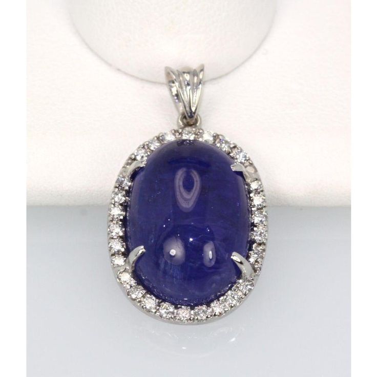 This is part of Chairish’s Fine Jewelry assortment.  WEIGHT: 7.8 grams MAIN STONE: Tanzanite, 20 cts OTHER STONES: Diamonds, .50 ct, VVS-VSI clarity, G-H color METAL: 18k white gold  This Tanzanite Cabochon Pendant with a Diamond surround is done in 18K White Gold and is brand new and never been worn. This tanzanite is a gorgeous shade of blue with nice metrics and it is large 21 Carats with a Diamond Border of .50 Carats of Diamonds. This pendant is high domed just like the matching ring and as Luxury Diamond Gemstones With Cabochon Cut, Luxury Diamond Cabochon Gemstones, Oval Diamond Gemstones For Formal Occasions, Formal Oval Diamond Gemstones, Luxury Sapphire Gemstones With Round Cut, Oval Gemstones With Prong Setting For Formal Occasions, Oval Diamond Cabochons With Polished Finish, Luxury Diamond Cabochons For Wedding, Luxury Oval Cabochon Diamond Gemstones