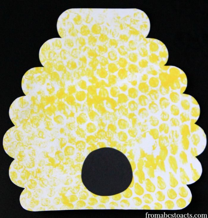 an animal made out of yellow and white paper with black dots on the bottom, in front of a black background