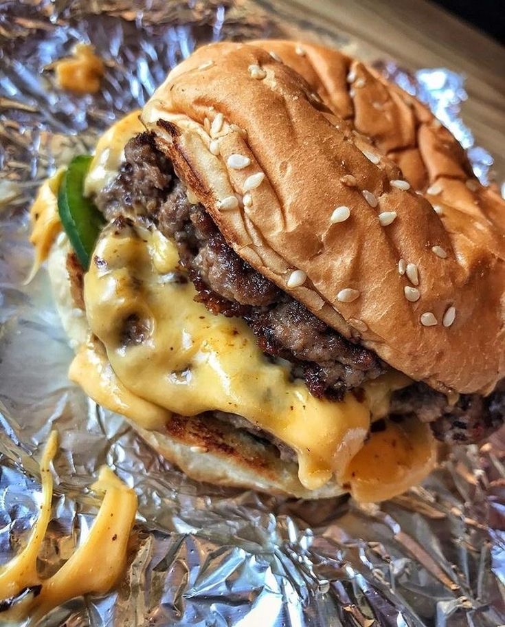 a cheeseburger on aluminum foil with french fries