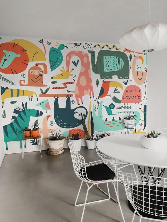 a white table and chairs sitting in front of a wall with colorful animals on it