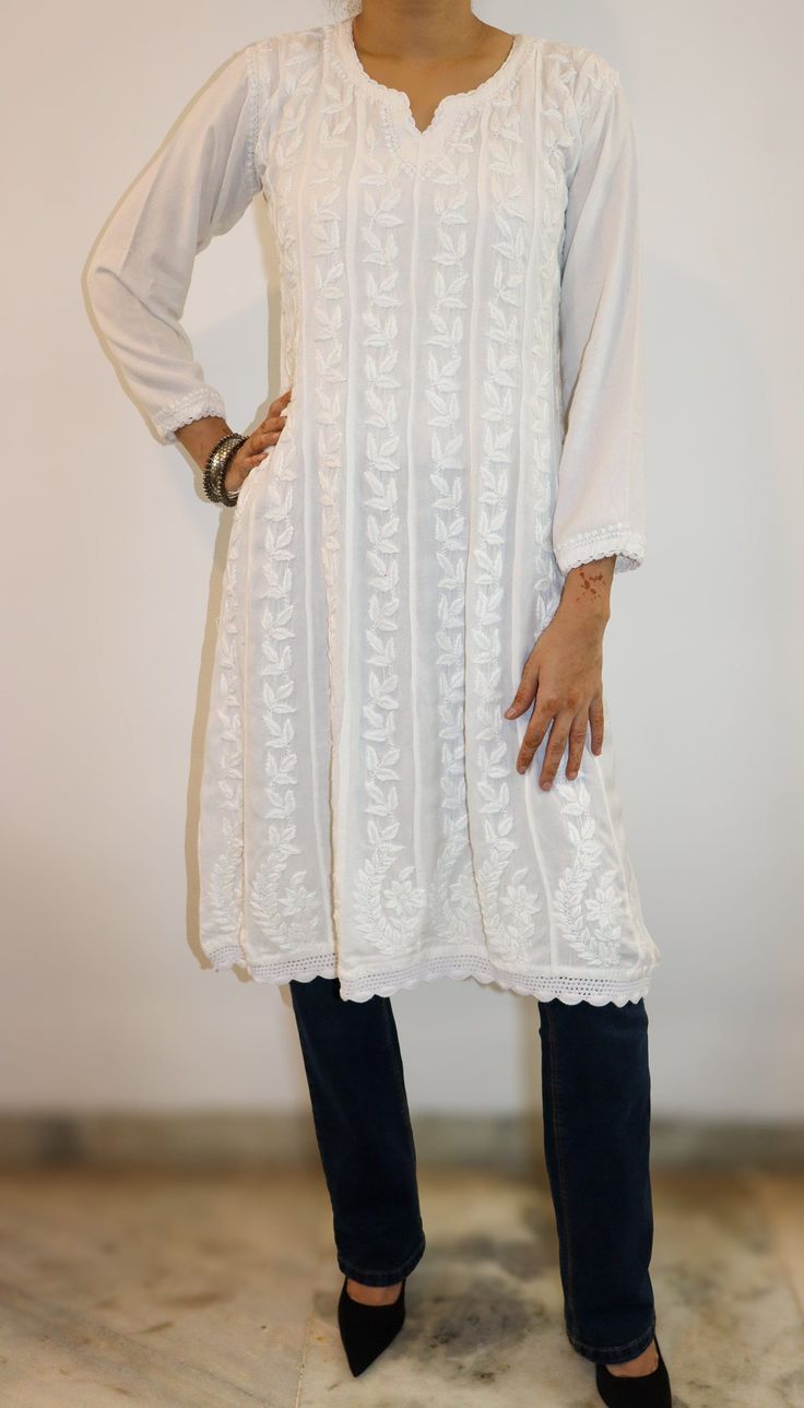 a woman standing in front of a white wall with her hands on her hips and wearing black shoes