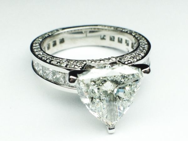 a close up of a diamond ring on a white surface with diamonds around the band