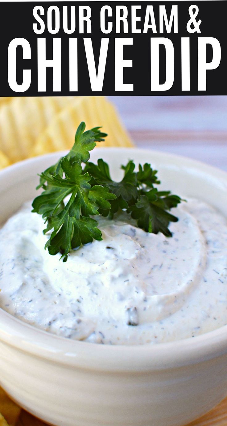 a white bowl filled with sour cream and cilantro dip next to some chips