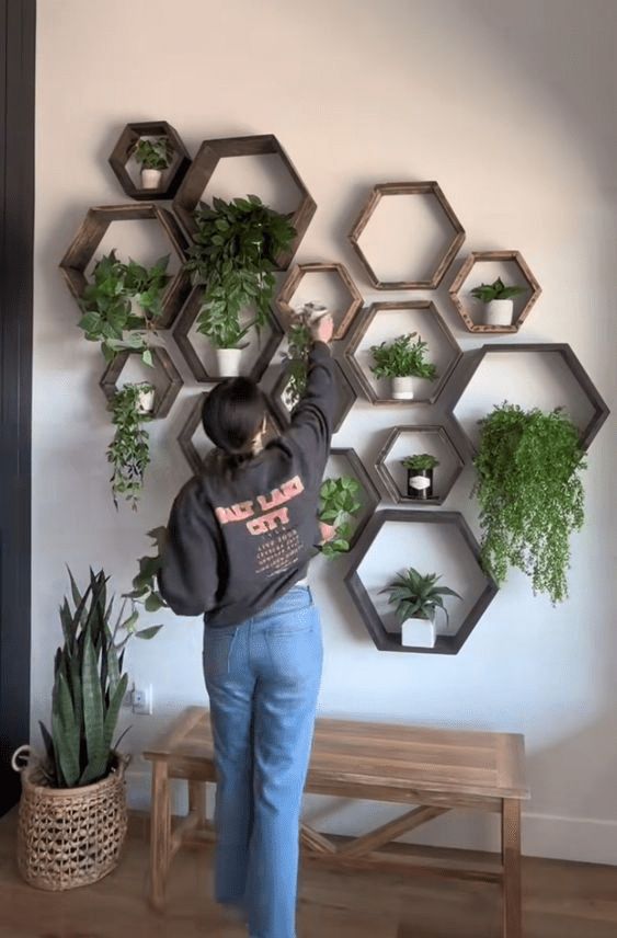 a woman standing in front of a wall mounted planter with hexagons on it