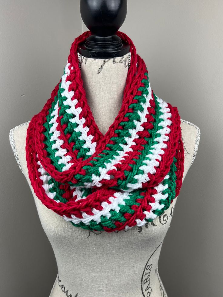 a red, white and green knitted scarf on top of a mannequin