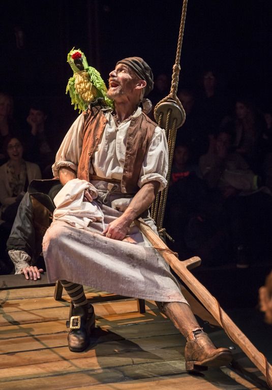 an old man sitting on a swing with a parrot perched on top of his head