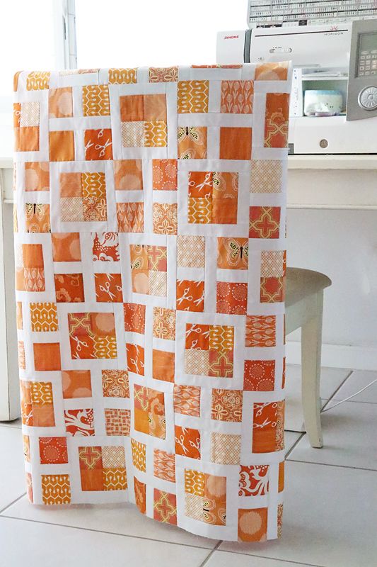 an orange and white quilt sitting on top of a table next to a microwave oven