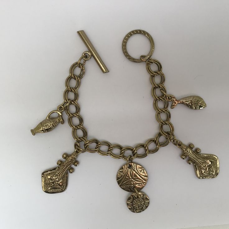 This is: An original vintage charm bracelet from the 60/70s. Lovely heavyweight gold tone brass curb bracelet with egraved ancient instrument, fish, urn and disc charms, fastening with a toggle clasp. Please see pics for size/weight/condition. Condition:  Great, no flaws. Any questions, please message me, thanks. I accept all returns - if you are not happy with your item, please message me before leaving feedback and I will be happy to deal with your concerns. I try my best to be as accurate as possible in my listings, but occasionally I will make a genuine mistake and will rectify it very quickly, just let me know, thanks. Bohemian Gold Charm Bracelet In Brass, Bohemian Gold Brass Charm Bracelet, Gold Bohemian Charm Bracelet Nickel Free, Bohemian Gold Metal Charm Bracelet, Vintage Charm Brass Bracelet, Bohemian Gold Charm Bracelet With Lobster Clasp, Gold Bohemian Charm Bracelet With Lobster Clasp, Gold Engraved Metal Charm Bracelet, Gold Bohemian Charm Bracelet