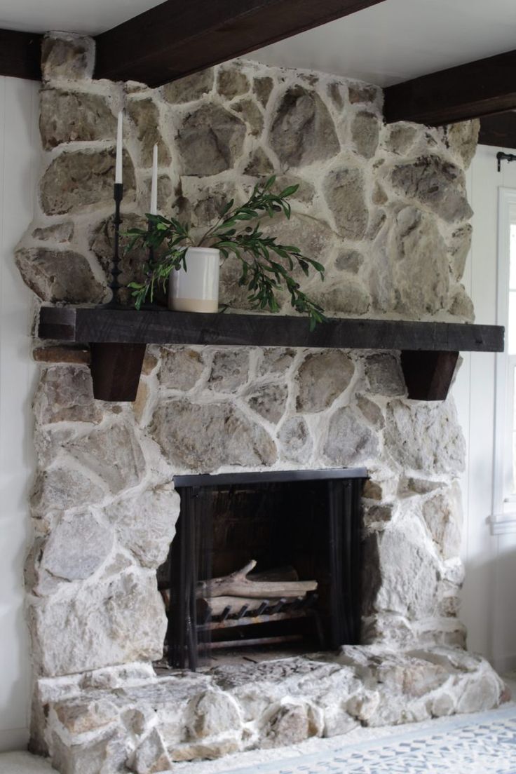 a stone fireplace in a living room with a plant on the mantel above it