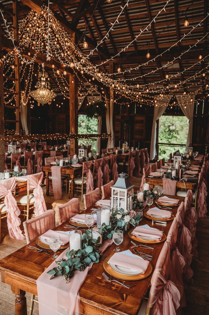 There is something magical about the look and feel of a barn wedding. It is a way to make a formal gathering to also be informal, relaxed, like a family get together. It also seems to make things stand out more, like the chandelier in this photo. Add in the beautiful farmhouse style tables and listen to the compliments. Wedding In Farmhouse, Farmhouse Theme Wedding, Wedding Rustic Decoration Indoor, Wedding Barn Lights, Wedding Venue Farmhouse, Rustic Princess Wedding, Country House Wedding Decor, Farmhouse Decor Wedding, Rustic Glam Decor Wedding