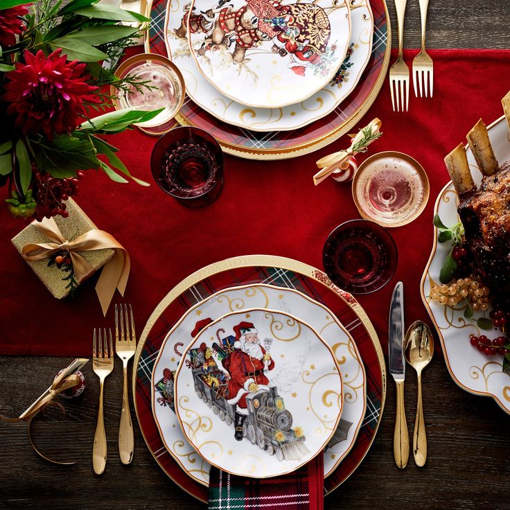 a table set for christmas with plates, silverware and red napkins on it