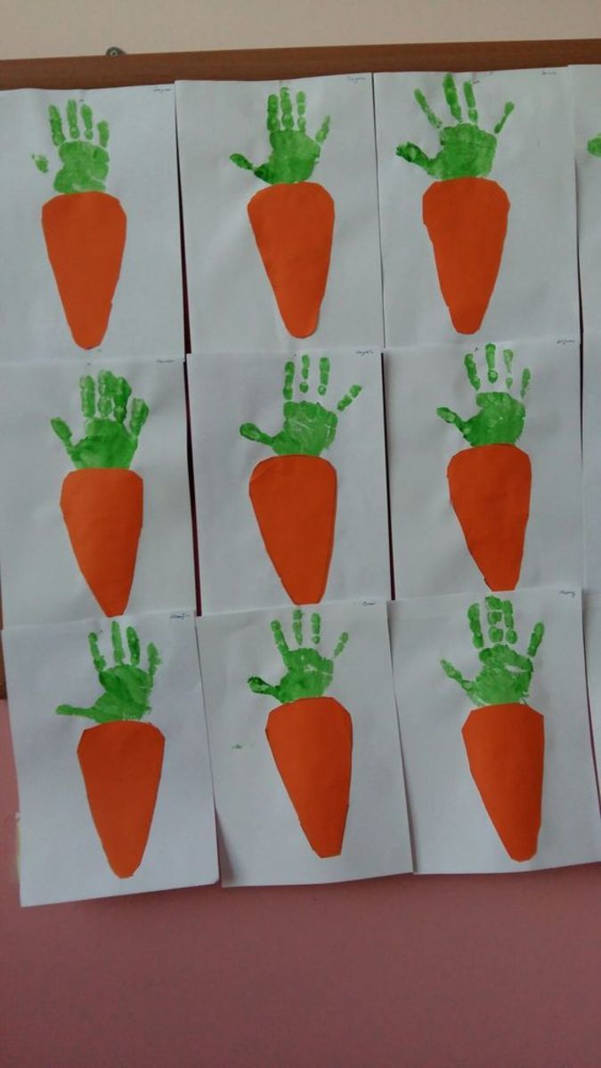 handprint carrots on white paper with green fingers