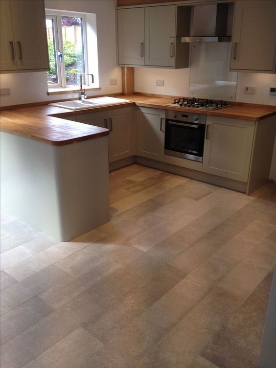 an empty kitchen with white cabinets and wood flooring on the counter top, in front of a window