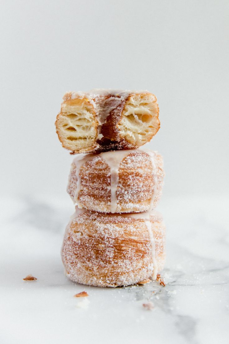 three donuts stacked on top of each other with icing and powdered sugar