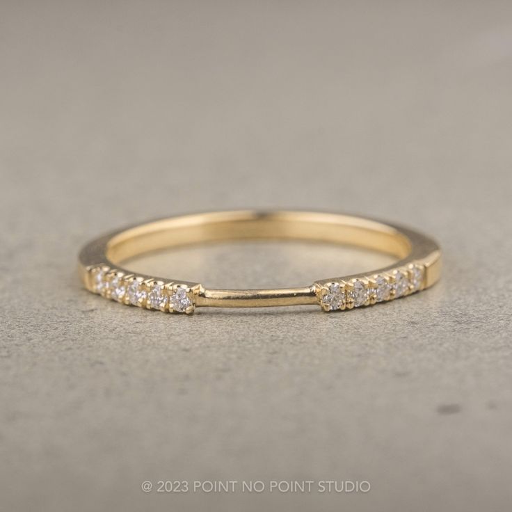 a yellow gold band with five diamonds on it, sitting on a gray surface in front of the camera