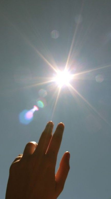 someone holding their hand up to the sun