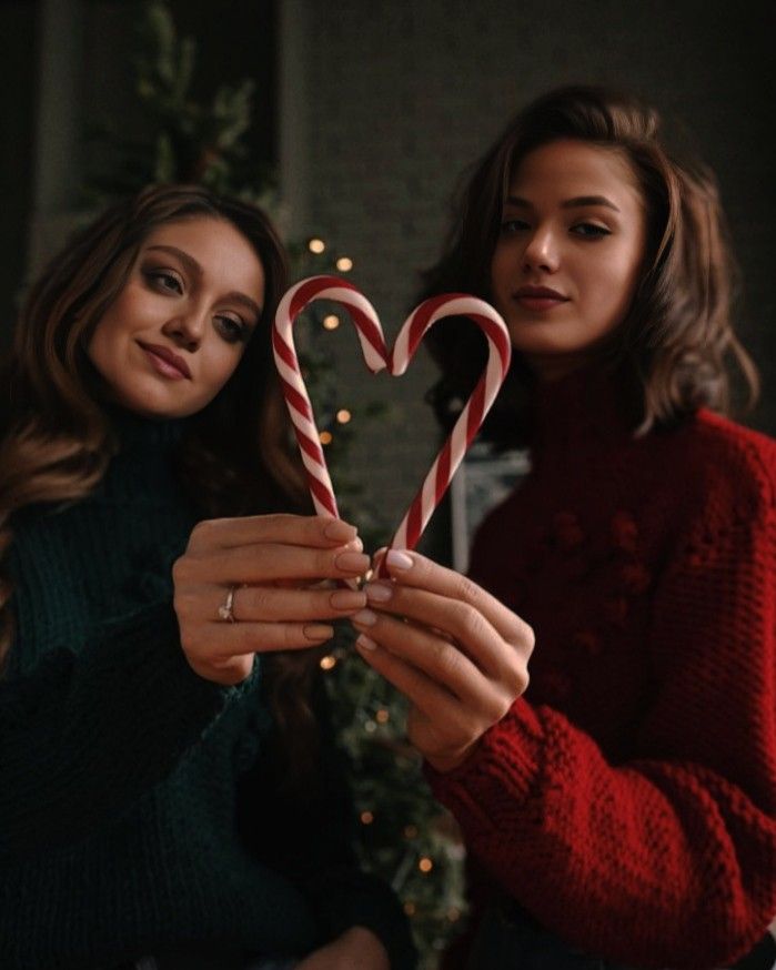 two women holding candy canes in front of a christmas tree