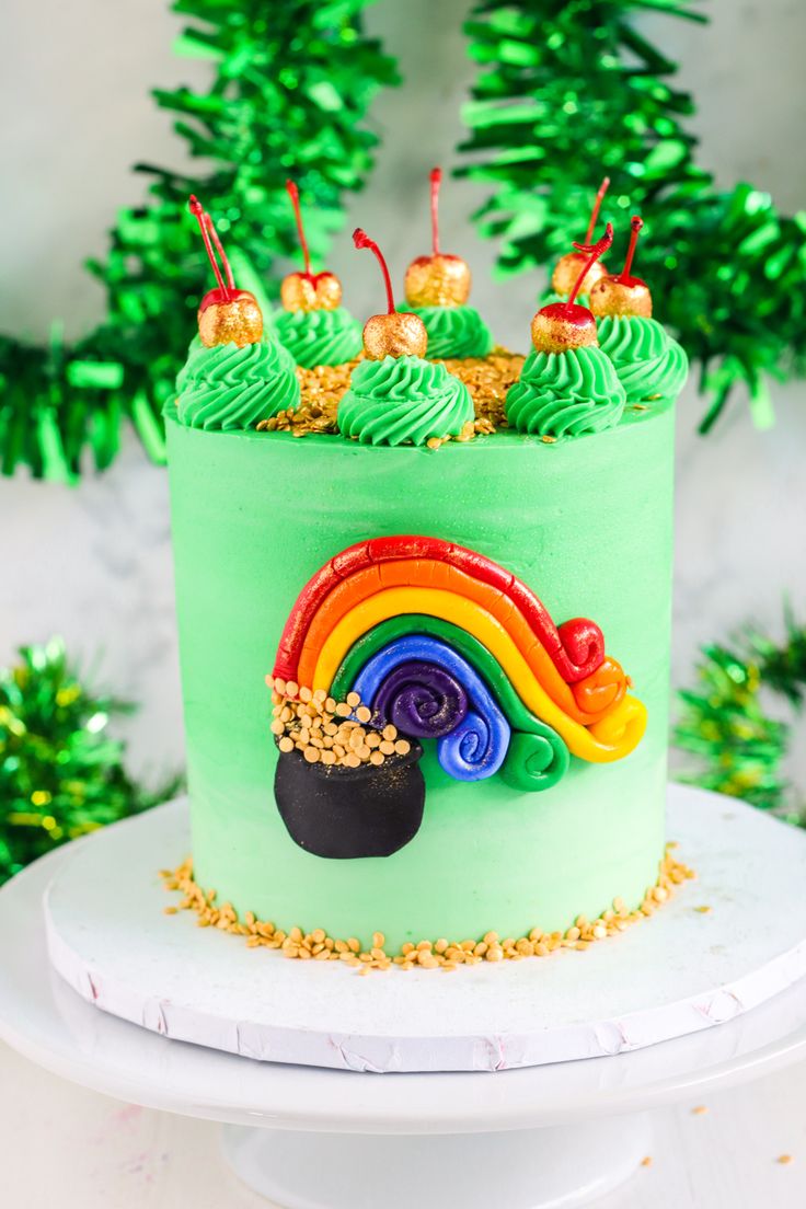 a green cake with rainbow frosting and gold sprinkles on the top