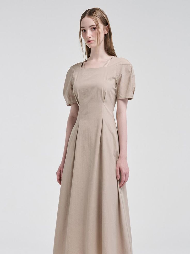 This product showcases a seamless blend of classic design with modern elements, featuring a square neckline paired with delicate pintuck details for a structured yet soft appearance. The design gracefully accentuates the waist before flaring into a flowing skirt, offering both style and movement. With its short puff sleeves, the dress captures a romantic essence, perfect for various occasions. - The square neckline provides a timeless elegance to the dress, while pintuck detailing adds a touch of sophistication.- Puff sleeves lend a feminine charm and gentle volume, complementing the fitted waist.- The dress flows into a full skirt, designed to move beautifully and give a flattering silhouette.- A handmade Cali medal decoration has been attached to the lower right side of the front pa Fitted Beige Midi Dress With Pleated Bodice, Fitted Square Neck Midi Dress For Daywear, Classic Fitted Midi Dress With Pleated Back, Classic Midi Dress With Straight Neckline, Classic Spring Midi Dress With Square Neck, Midi Dress With Pleated Bodice, Feminine Square Neck Dress For Work, Feminine Pleated Square Neck Dress, Classic Midi Dress With Pleated Back