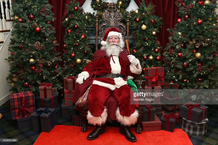 a man dressed as santa claus sitting in front of christmas trees