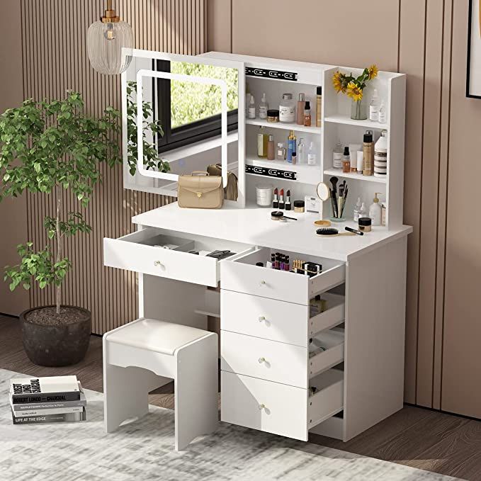 a white desk with drawers and a mirror on it next to a potted plant