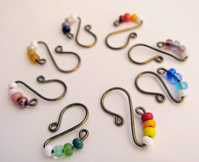 several pairs of earrings are arranged in a circle on a white surface, with various colored beads hanging from them