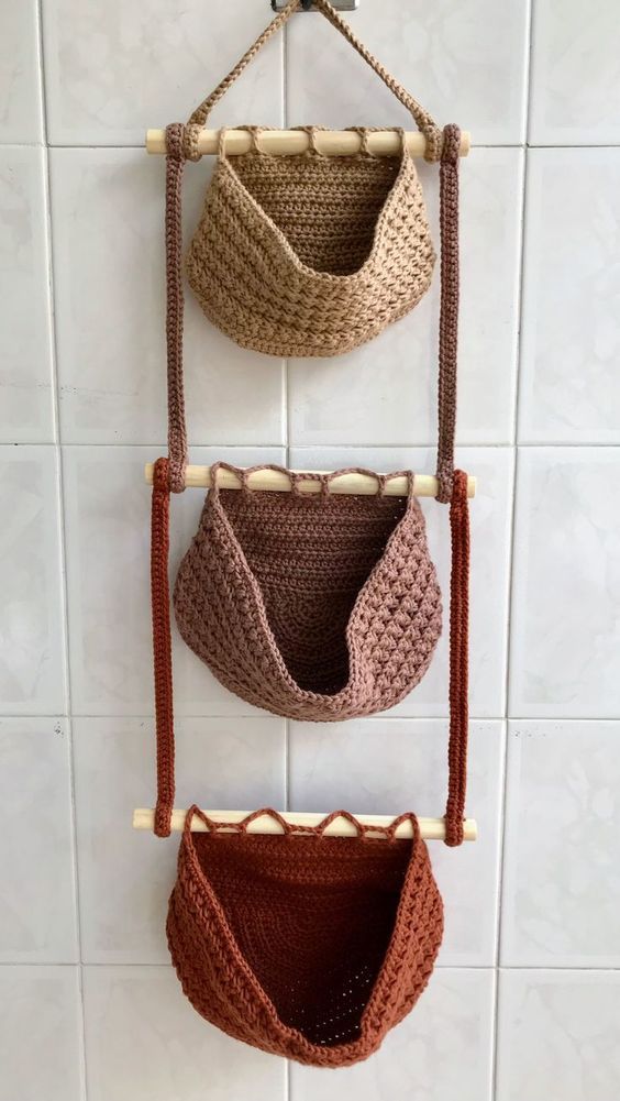 three crocheted purses hanging on a wall in a bathroom with white tiles