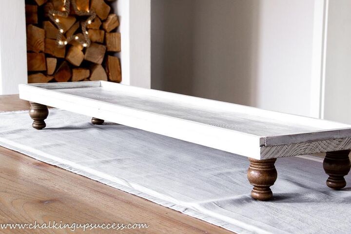 a white bench sitting on top of a wooden floor next to a pile of logs