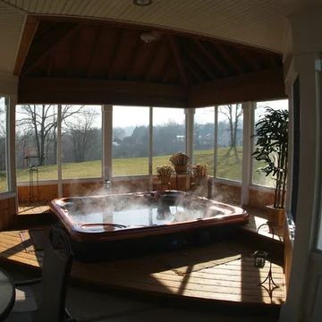 a hot tub in the middle of a room with large windows and wooden floors on both sides