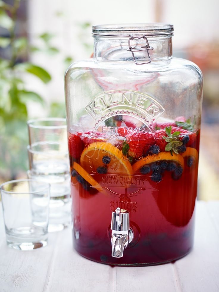 a beverage dispenser filled with fresh fruit and ice sits on a table