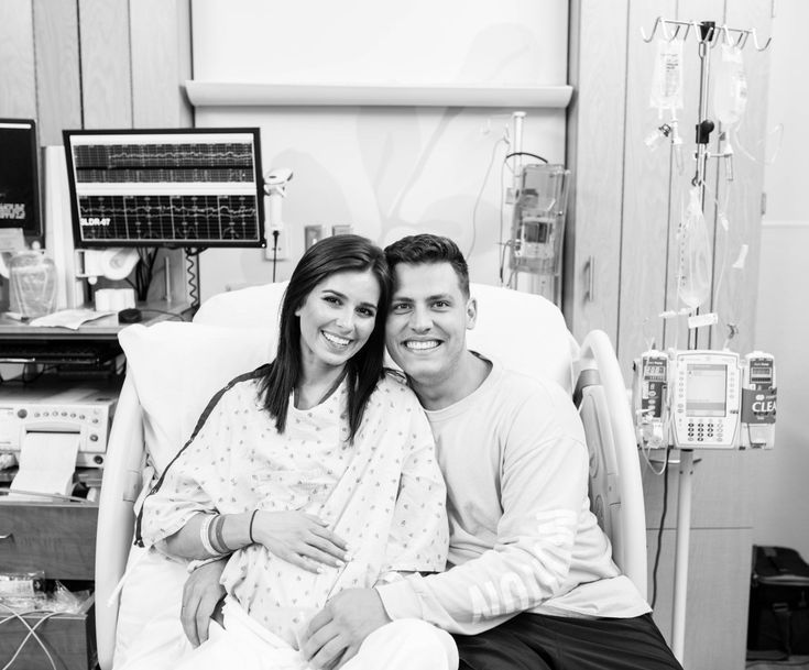 a man and woman sitting in a hospital bed smiling at the camera while holding each other