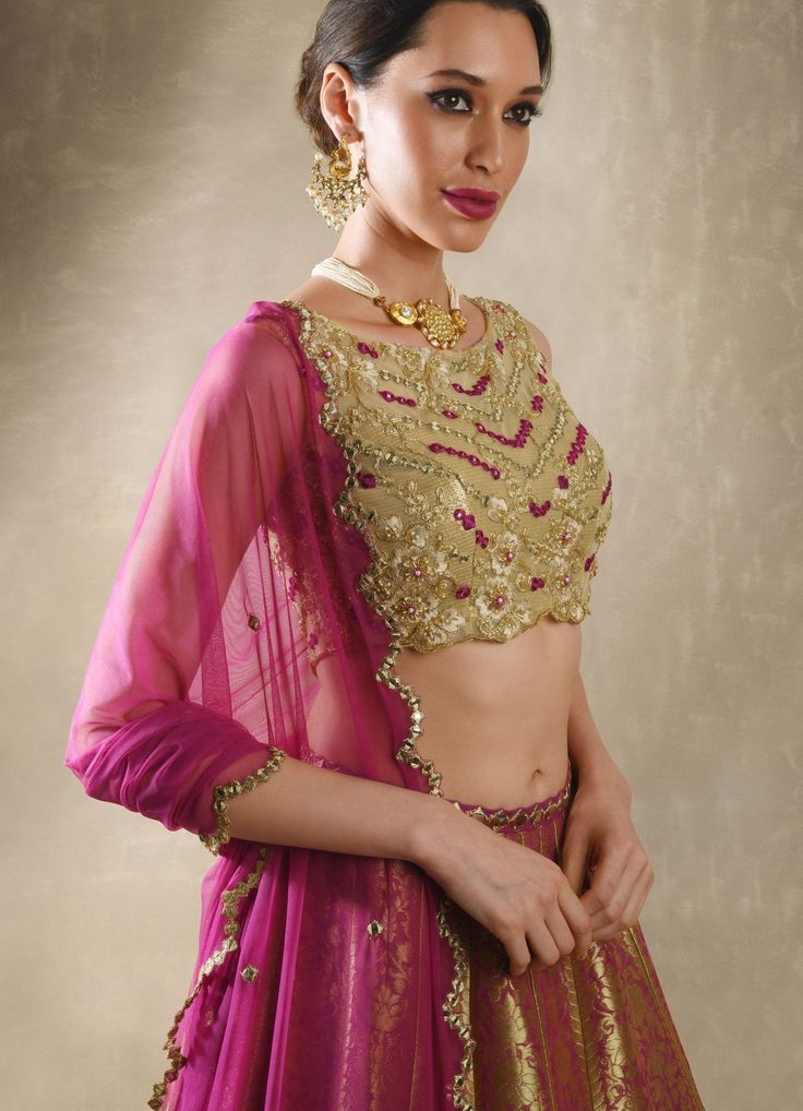 This exquisite Purple Pink Embroidered Banarasi Lehenga Set is crafted from luxurious Banarasi fabric, featuring rich kalidar purple pink lehenga adorned with a striking mirror-embellished belt and border that add a glimmer of sophistication to its traditional weave. Teamed with a classic mirror work blouse, intricately embellished with dori, mirrors, beads, and sequins, exuding an opulent charm. A lightweight tulle dupatta completes the look, delicately sprinkled with mirror buttis and finished Bollywood Semi-stitched Choli For Diwali, Elegant Choli With Gota Work For Diwali, Elegant Gota Work Choli For Diwali, Elegant Navratri Choli With Gota Work, Elegant Gota Work Choli For Navratri, Transitional Season Gold Lehenga With Gota Work, Transitional Gold Lehenga With Gota Work, Festive Lehenga With Resham Embroidery, Kundan Saree Set With Pallu