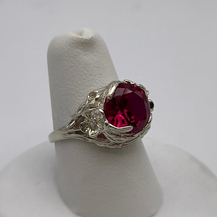 Gorgeous Floral Ruby Ring in Sterling Silver  * 4ct Ruby measures 10mm Round  * Solid Sterling Silver  * Size 7 - sizing available  Also available in 10k, 14k and 18k Gold - message me for current Gold pricing.    Hallmarked and Gift Ready!  This 4ct Ruby is Laboratory Grown. It is identical to natural in every way, including Chemistry, Composition & Hardness with flawless clarity & excellent color refraction.  TIMELESS, BEAUTIFUL & UNIQUE FINE ART JEWELRY! Formal Cubic Zirconia Ruby Ring, Formal Ruby Gemstone Ring, Formal White Gold Ruby Ring With Round Stone, Formal Cubic Zirconia Ruby Ring With Round Band, Formal Ruby Ring With Cubic Zirconia In Round Band, Formal Ruby Ring With Round Stone In White Gold, White Gold Ruby Jewelry, Silver Rings With Lab-created Ruby, Classic Round Ruby Jewelry