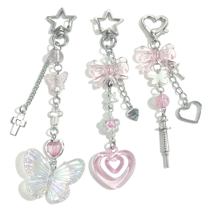 three key chains with charms attached to them, one has a butterfly and the other has a heart