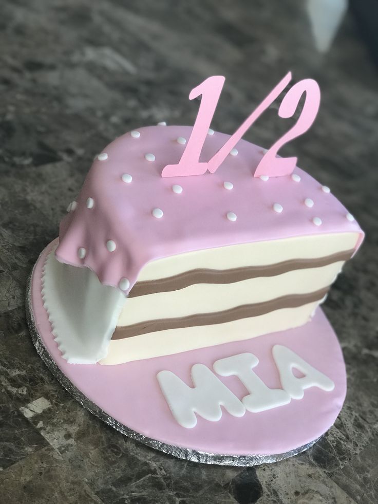 a pink and white cake with the number twelve on it's side sitting on a table