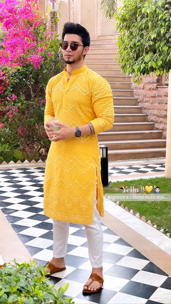 a man in yellow is standing on a checkerboard floor with his hands clasped